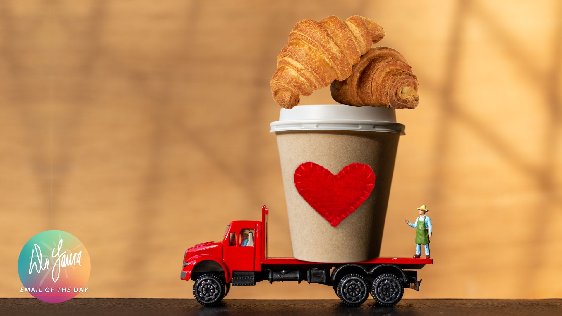 A croissant sits on a to-go coffee cup on a red truck
