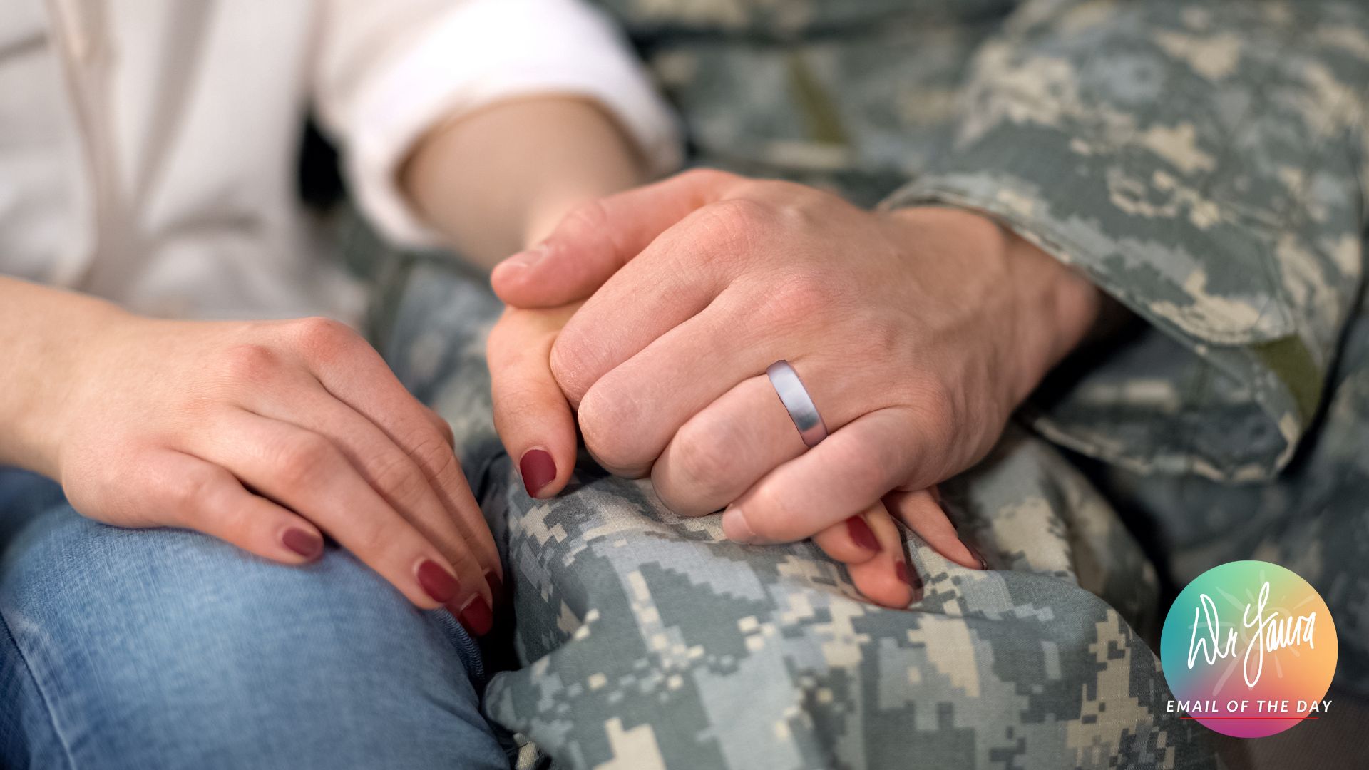 Man in army uniform holds woman's hand on his leg