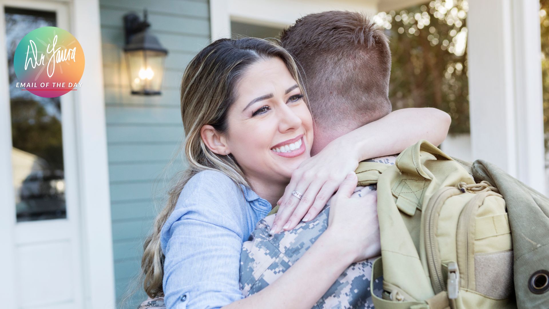 Woman in blue shirt hugs man in military uniform