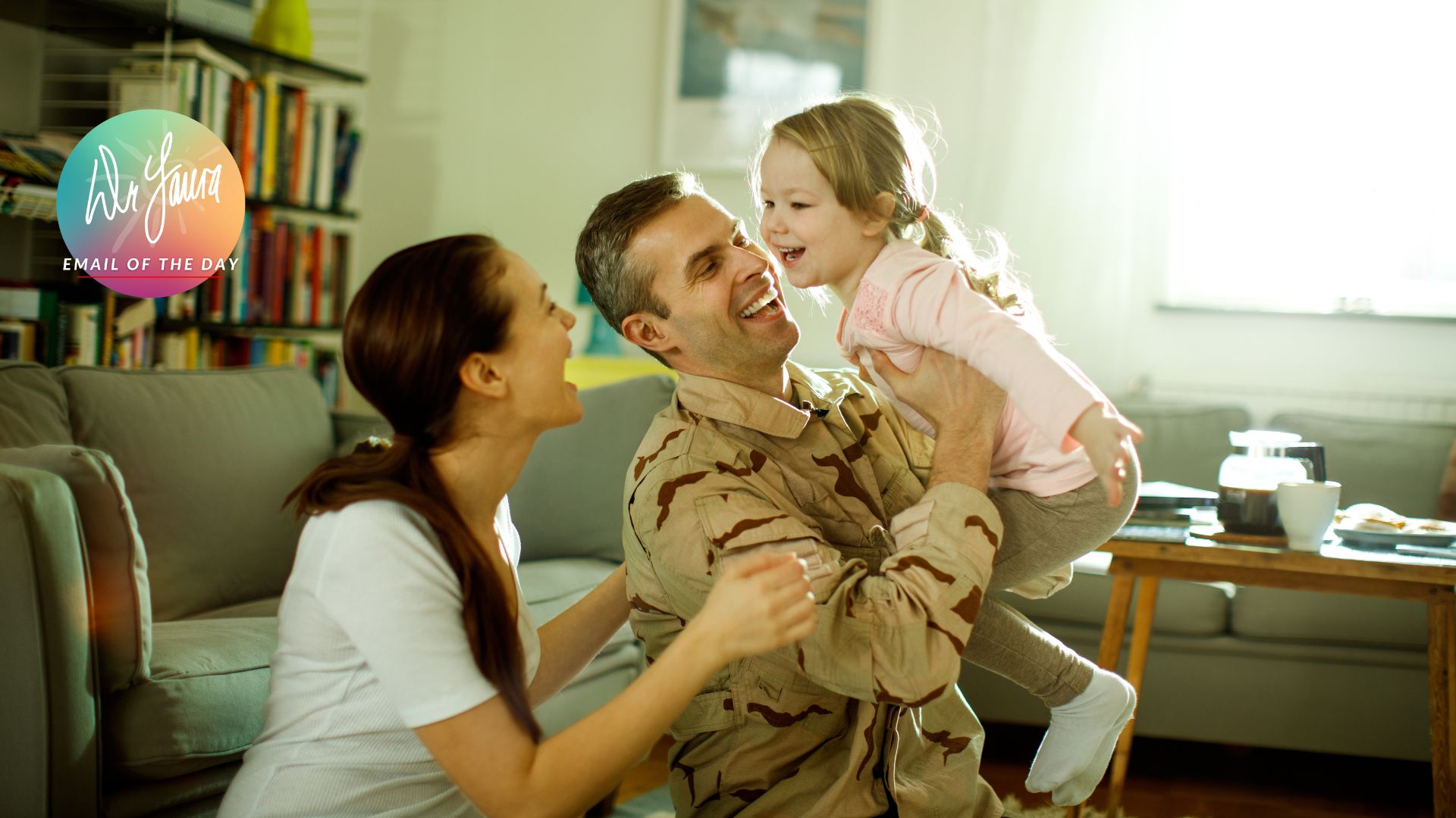 Man in military uniform holds little girl in his arms while woman in white shirt holds onto his arms