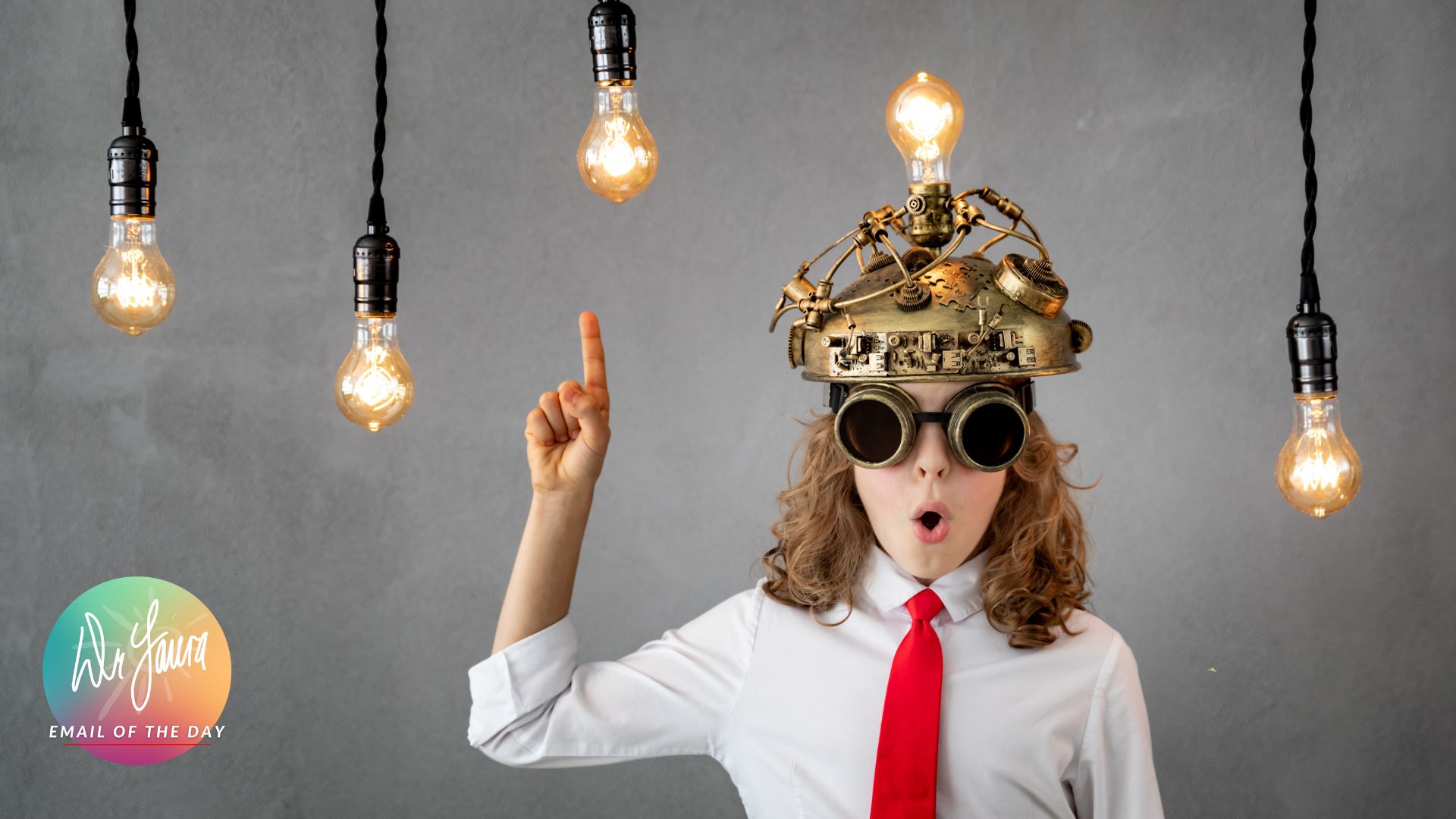 Young boy with steampunk glasses and brain cap opens mouth in surprise while pointing up to two hanging light bulbs