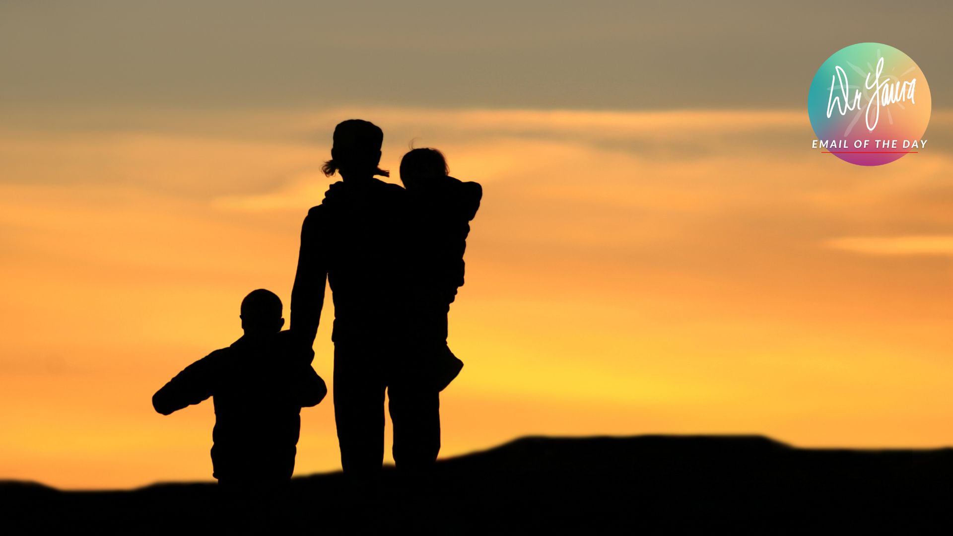 Silhouette of woman holding young child in her arms while holding hands with a small child outside
