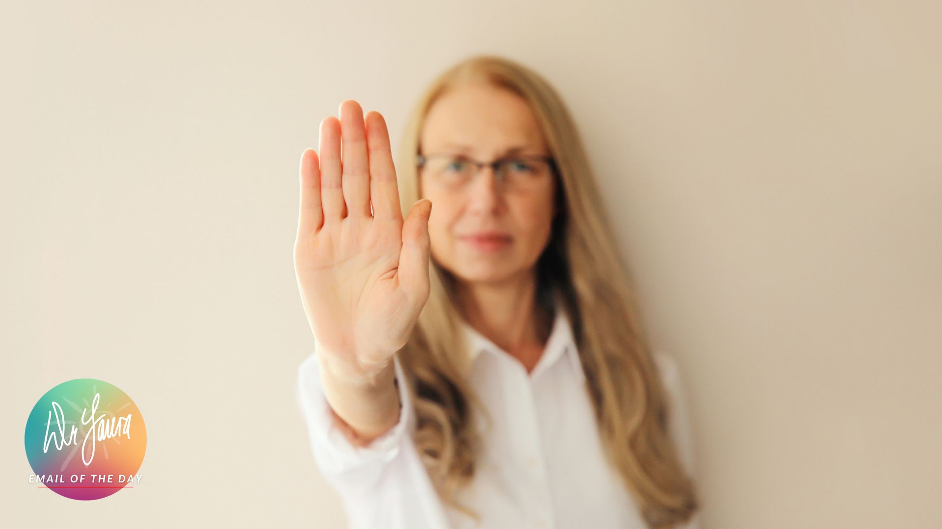 Older woman wearing glasses holds out palm in front of her