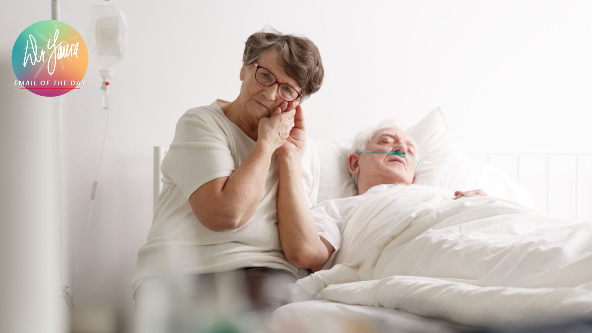 Woman sits on the edge of a hospital bed while holding hands of man laying down