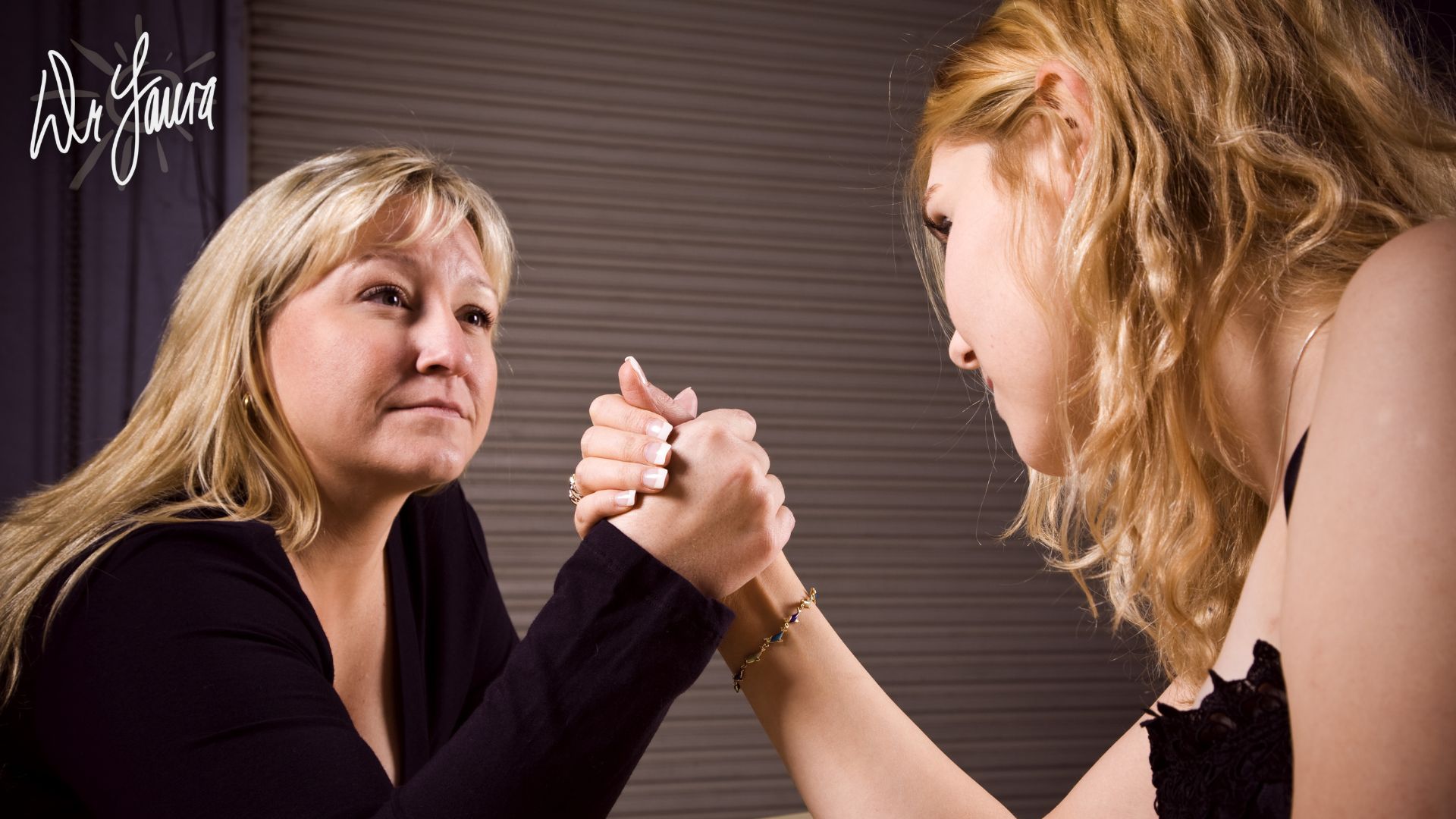 Woman and teen girl armwrestle
