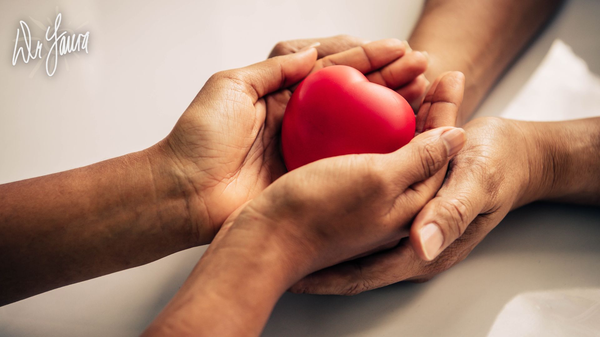 Two hands are placed on top of each other while cradling a heart-shaped object